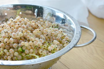 White currants in a strainer bowl on wooden table