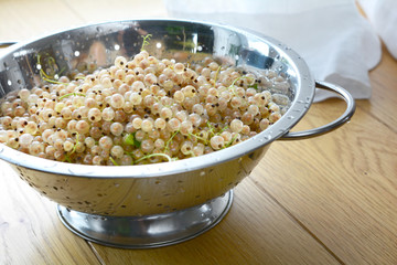 White currants in a strainer bowl on wooden table