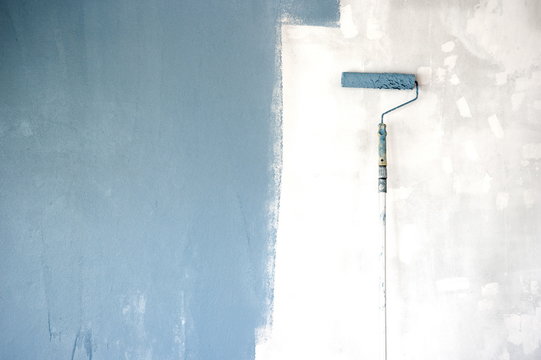 blue painting with roller brush on the repair cement wall construction background