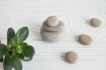 Pyramids of white zen stones with green leaves on white background. Concept of harmony, balance and meditation, spa, massage, relax