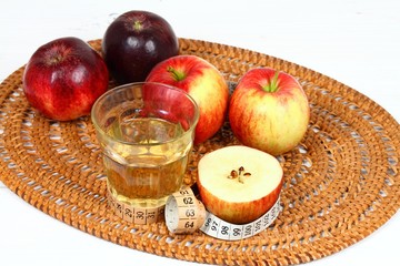 Apple vinegar good for diet / Fersh apples, measuring tape, cut bottle and glass on white wooden table