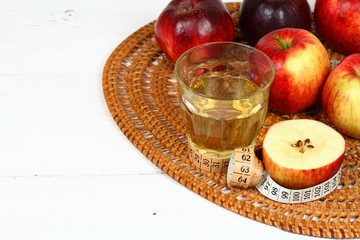 Apple vinegar good for diet / Fersh apples, measuring tape, cut bottle and glass on white wooden table