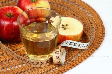 Apple vinegar in glass / Fersh apples and measuring tape around on white wooden table