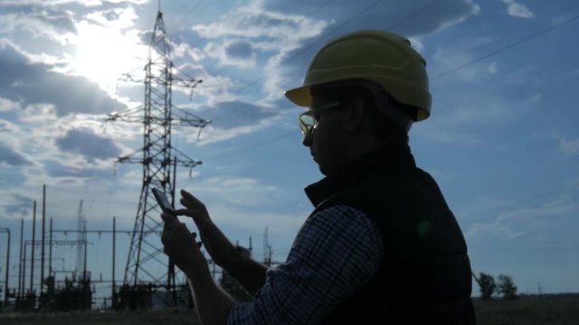 silhouette of engineer electricity talking and use phone during sunset