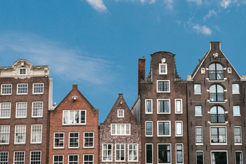 Traditional houses in Amsterdam in the Netherlands in a row against the blue sky.