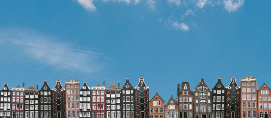 Panorama of panoramisch uitzicht. Traditionele huizen in Amsterdam in Nederland op een rij tegen de blauwe hemel.