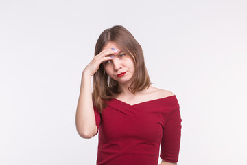 Fototapeta premium Young sad woman with red lips thinking with hand on her forehead