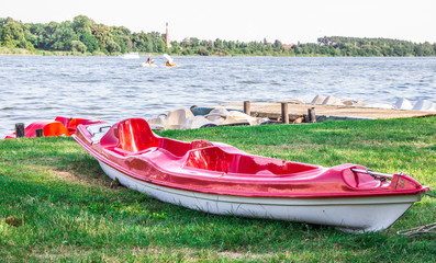 A red canoe on the shore of the lake.