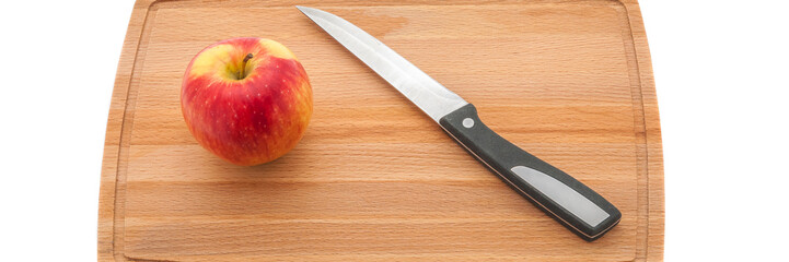 Ripe red juicy apple and knife on a cutting board made of dark wood.
