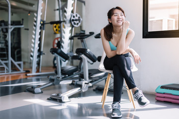 Fototapeta premium Women's exercise in fitness, relaxation gym, after sport training with dumbbell,Fitness woman taking a break after workout.