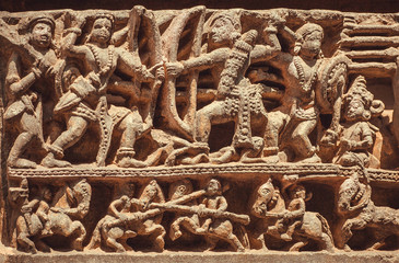 South Indian temple relief with battle scene. warriors and riders with weapon fighting on wall of Hindu structure from 12th century, Halebidu, India
