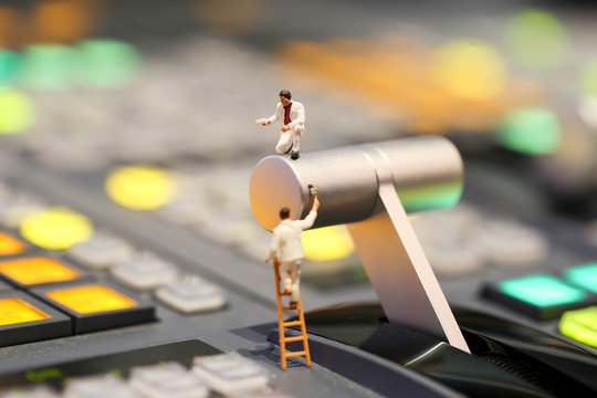 Miniature people : worker painting on switcher control of Television Broadcast,color buttons