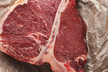 Raw t-bone steak on craft papper closeup