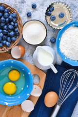 Food background. Ingredients for baking: flour, eggs, berries, chocolate on a concrete background.