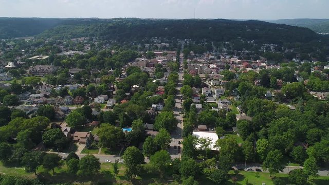 A laterally-moving aerial establishing wide shot of the small western Pennsylvania town of Beaver. Business district in the distance and neighborhood in the foreground. Pittsburgh suburbs.  	