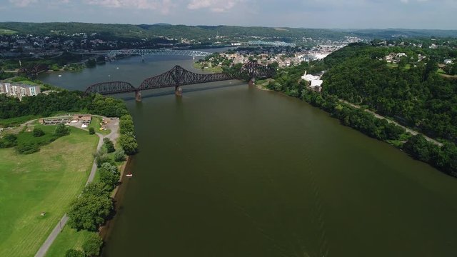 A high angle aerial wide shot of boats and bridges over the Ohio River in western Pennsylvania on a summer day. Pittsburgh suburbs.  	