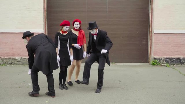 Four funny mimes play scenes on city street