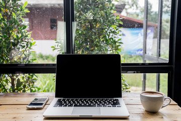 laptop with mobile phone and a cup of fresh coffee latte art on wooden table.