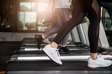 Young asian people running on a treadmill in health club.