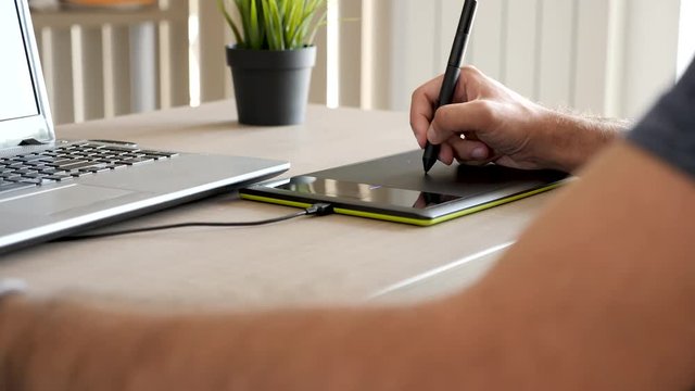 Man hands holding a pen and drawing on digital tablet. Close up footage of artist working