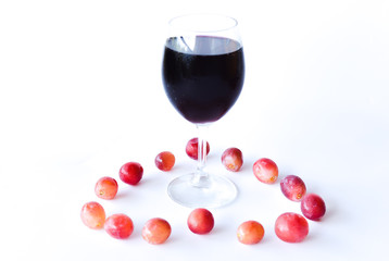 ripen red grapes and a glass of wine isolated on white background. selective focus.