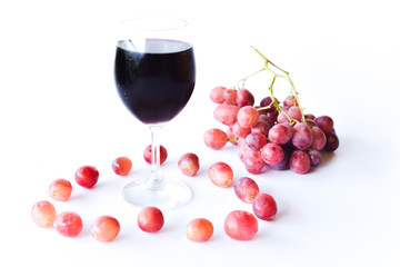 ripen red grapes and a glass of wine isolated on white background. selective focus.