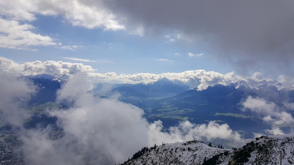 View on Tirolean Alps from Nordkette mountain range through breaking clouds and mist