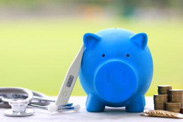 Blue piggy with thermometer and medicine on natural green background,Save money for Medical...