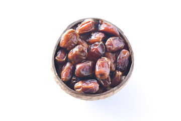 dried dates or kurma in a coconut shells isolated on white background. selective focus.