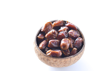 dried dates or kurma in a coconut shells isolated on white background. selective focus.