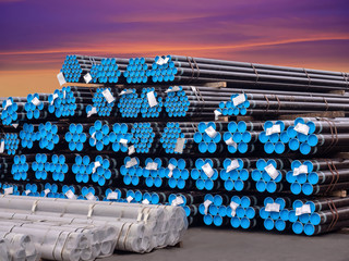 ​​Stacking steel pipe in bundles at industrial yard for exporting.