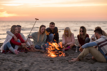 Group Of Young Friends Sitting By The Fire at beach