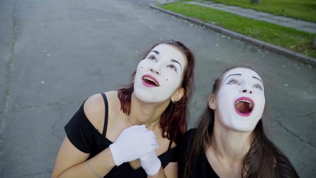 Two girls mimes imitate embarrassment when see camera