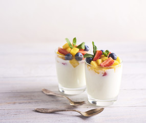 Homemade Greek yogurt with granola, mint, blueberries, mango and strawberry in a glass on white  background