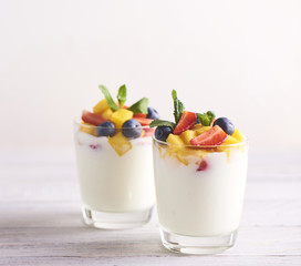 Homemade Greek yogurt with granola, mint, blueberries, mango and strawberry in a glass on white  background