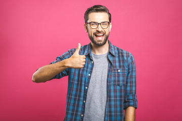 Portrait of young man in glasses showing thumbs up isolated over pink background