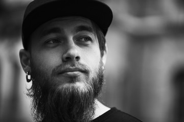 Dramatic Portrait of Handsome bearded man with piercing in black cap