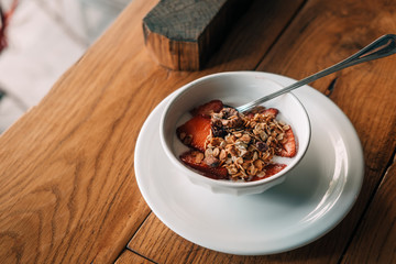 Yogurt with granola, strawberries on wooden coffee table. Hipster coffee shop. Food photography concept. Copy space