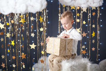 Cute little boy with a present in a studio with a gold stars decor