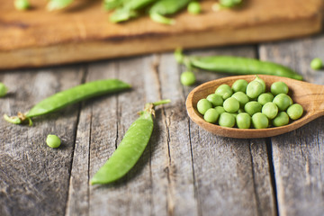 Close-up view of Hearthy fresh green peas and pods spoon on rustic background