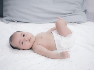 Asian baby lying playing on the bed, Baby development stages of 3 month old.