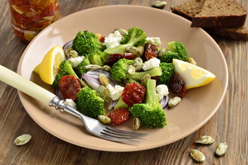 Salad with broccoli, dried tomatoes, feta, onions and pumpkin seeds