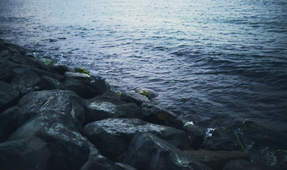 Splashing wave on Stone in sea on sunset time.