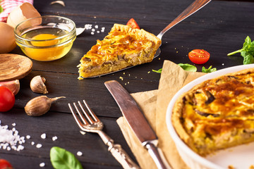 A piece Homemade quiche lorraine with chicken, mushrooms and cheese, kitchenware and ingredients