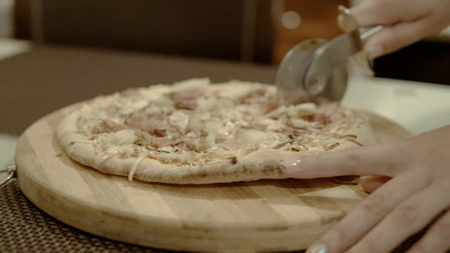 Slicing home made pizza on wooden board close-up 4k.