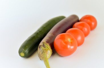 Egg plant, tomatoes, and cucumber isolated on bright background. Selective focus.