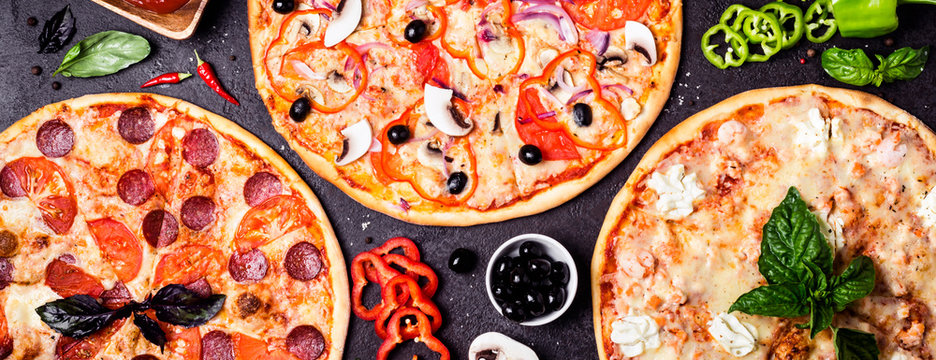 selection of different pizzas on a black background and ingredients. Peperoni, Vegetarian and Seafood Pizza