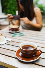 Hot americano coffee in the cup with Asian woman drink coffee in the coffee shop.