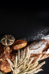 Different kinds of bread and bread rolls on board from above. Kitchen or bakery