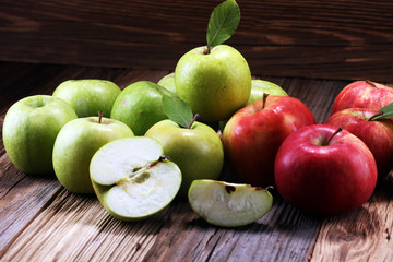 Ripe red apples with leaves on wooden background.